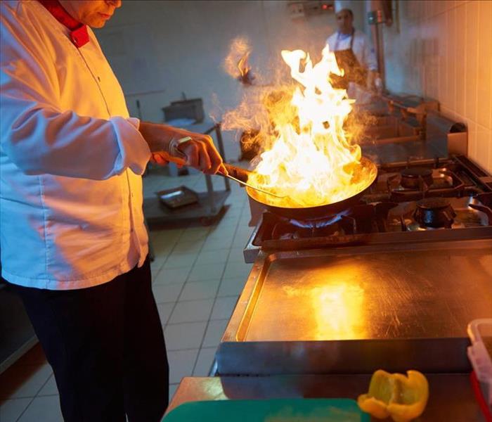 Image of a person cooking with fire on top of frying pan