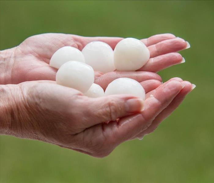Image of a person holding hail the size of a golf ball.
